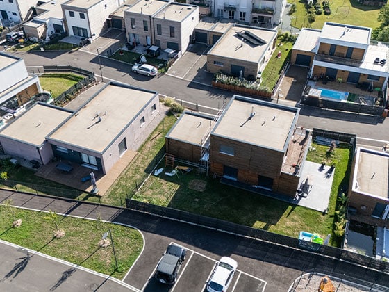 Vue aérienne de plusieurs maisons booa à toit plat et de leur jardin.